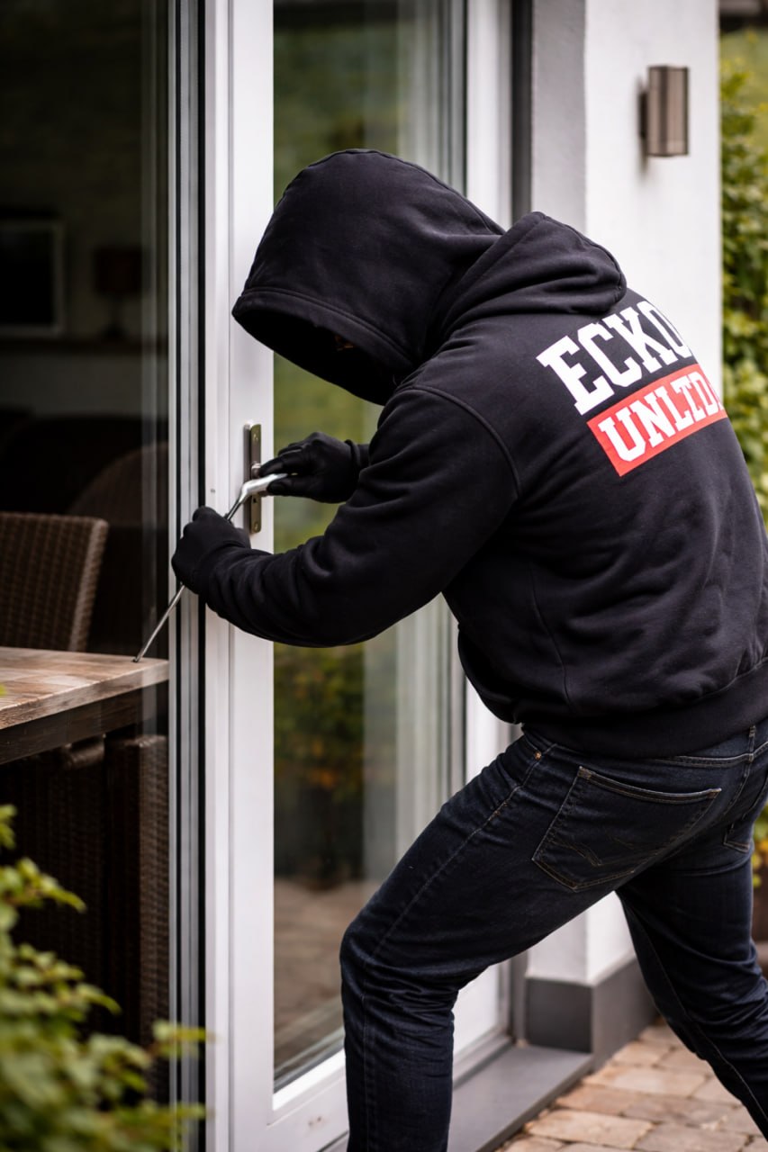 Mit Kapuze vermummter Einbrecher versucht eine Terassentür zu öffnen